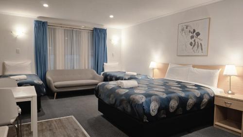 a hotel room with a bed and a couch and a chair at Tropicana Motor Inn in Cowes