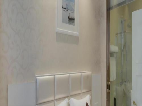 a bathroom with a white wall with a picture on the wall at Changshu Please Hotel in Changshu
