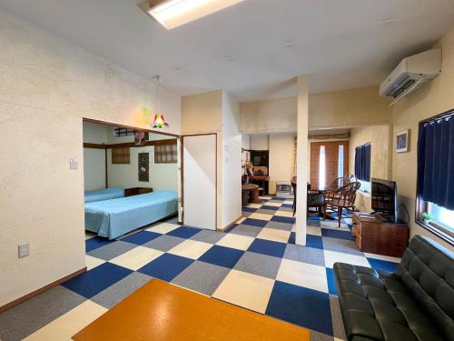 a living room with a blue bed and a checkered floor at Natsumi no Sato in Biei