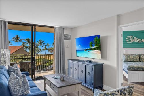 a living room with a blue couch and a tv at Hip Oceanfront Resort Vistas in Kihei