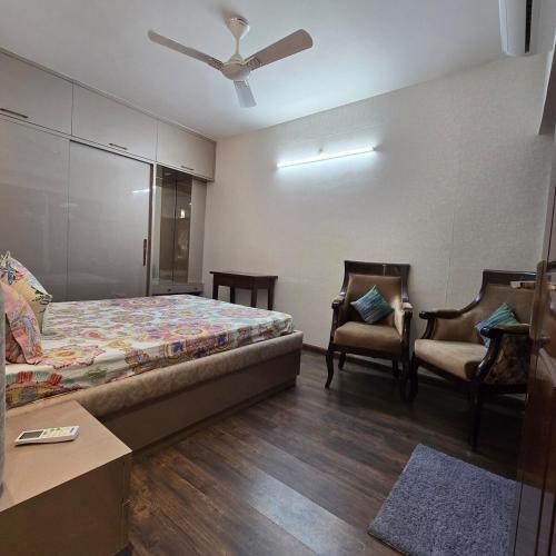 a bedroom with a bed and two chairs at Luxury Studio Apartment in Bareilly in Bareilly