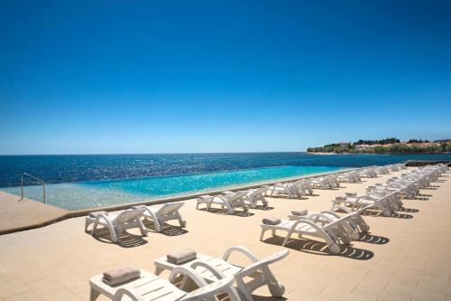 a row of chaise lounge chairs on a beach at Aminess Planet Camping Holiday Homes Sirena in Novigrad Istria