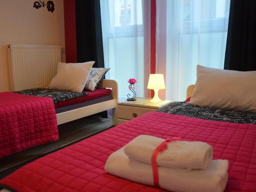オルシュティンにあるApartamenty Szczęśliwe Snyのベッドルーム1室(赤いシーツと赤い毛布のベッド2台付)