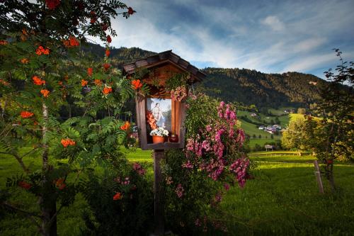 a bird house with flowers on it in a field at Ferienwohnung Bognerhof in Sankt Veit im Pongau