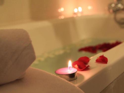 a candle in a bath tub with two roses at Midland Hotel in Phnom Penh