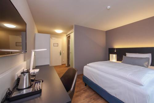 a hotel room with a bed and a desk with a computer at Design & Lifestyle Hotel Estilo in Aalen