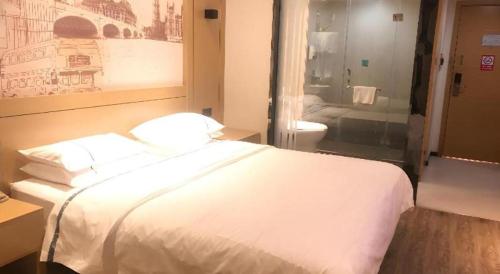 a hotel room with a white bed and a bathroom at City Comfort Inn Wuhan Baibuting in Wuhan