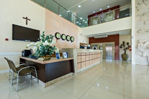 a lobby with a reception desk and a cross on the wall at Hotel Thomasi Express in Maringá