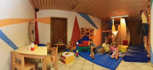 a room with two children sitting on mats in a play room at Alpen Wohlfühlhotel Dörflwirt in Hainzenberg