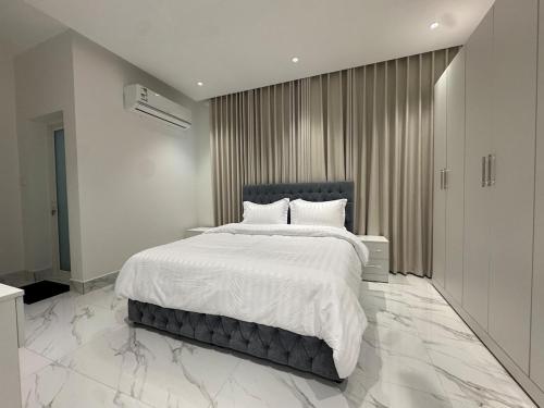 a bedroom with a large bed with white sheets at Najd Cozy Apartments in Dammam