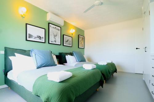 Pet Friendly Sleeps 8 Bowen Holiday House في بوين: سريرين في غرفة نوم مع جدران خضراء