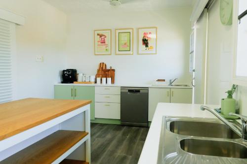 Pet Friendly Sleeps 8 Bowen Holiday House في بوين: مطبخ مع حوض وثلاجة