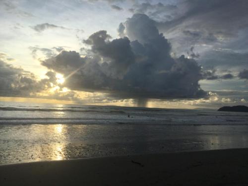 a storm cloud over the ocean with a person on the beach at La Perlita in Jacó