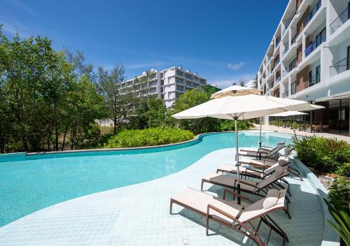 a swimming pool with lounge chairs and an umbrella at Laya Resort Phuket in Layan Beach