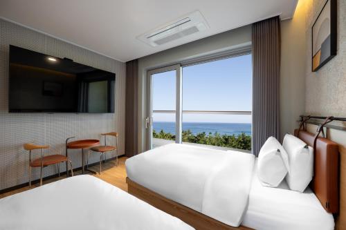 um quarto com duas camas e uma janela grande em Hotel Hound Gangneung Gyeongpo em Gangneung