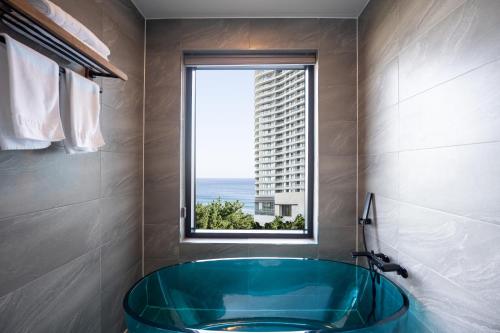 uma casa de banho com uma banheira azul e uma janela em Hotel Hound Gangneung Gyeongpo em Gangneung