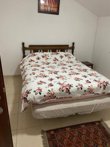 a bed with a floral comforter on it in a bedroom at Apartment for 4 guests in Karmiel