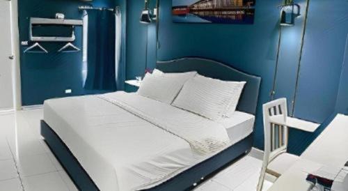 a blue bedroom with a bed with white sheets and pillows at HUBBLE HOTEL in Hat Yai