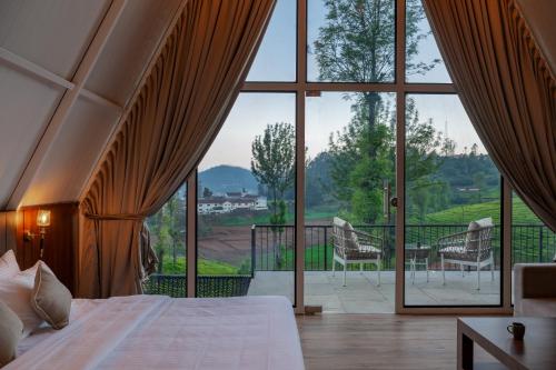a bedroom with a bed and a large window at Triangle Valley in Ooty