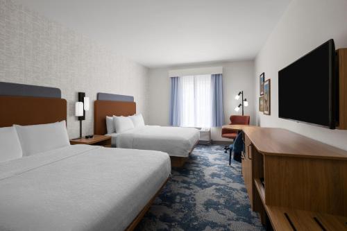 Hampton Inn & Suites Southern Pines-Pinehurst في Aberdeen: غرفة فندق بها سريران وتلفزيون بشاشة مسطحة