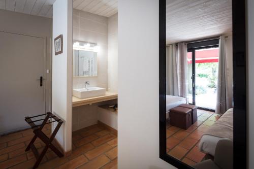 a bathroom with a sink and a bed and a mirror at Logis des Magnans - le Murier - in Sauve