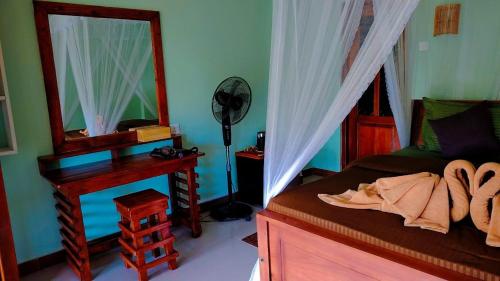 a bedroom with a bed and a desk and a mirror at Zen Garden Palace in Ella