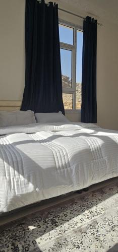 a large white bed in a bedroom with a window at Sunset view of Jebel Shams in Misfāh