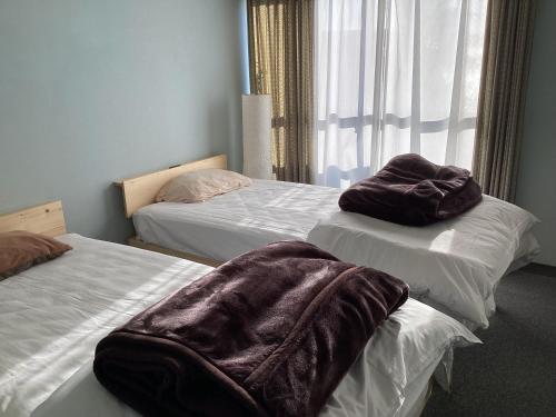 a room with two beds with brown blankets on them at 勝浦シーサイドホテルKatsuura Seaside Hotel Apartment-type hotel without kitchen in Nachikatsuura