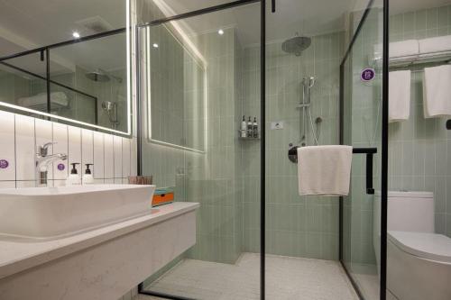 Un baño con lavabo y ducha de cristal. en Wanda Yi, Suite Xishuangbanna, en Jinghong