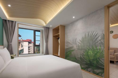 Un dormitorio con una cama y una ventana grande. en Wanda Yi, Suite Xishuangbanna, en Jinghong