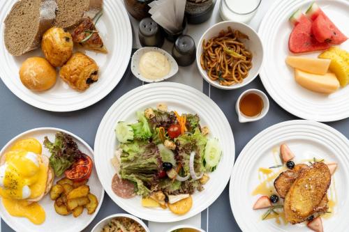 バンコクにあるGM Estate Hotel and Executive Apartments, Bangkok Sukhumvit 20の白い皿に食べ物が盛られたテーブル