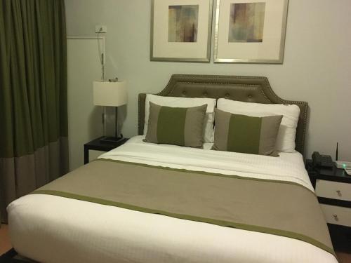 a bedroom with a large bed with green and white pillows at Avant Serviced Suites - Personal Concierge in Manila
