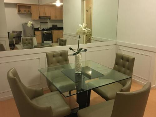 a dining room with a glass table and chairs at Avant Serviced Suites - Personal Concierge in Manila