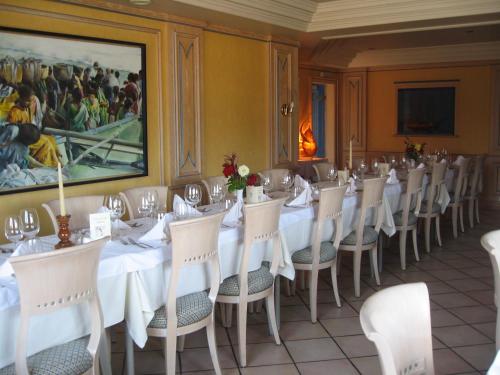 a dining room with white tables and chairs and a painting at Hôtel Restaurant Oberlé in Kilstett