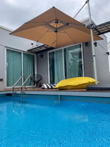 un parasol assis à côté d'une piscine dans l'établissement Home stay Ev Coffeehouse, à Ban Map Khao Wan