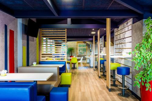 un restaurant avec des tables et des chaises bleues et vertes dans l'établissement ibis budget Issy Les Moulineaux Paris Ouest, à Issy-les-Moulineaux