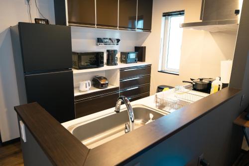 a kitchen with a sink and a refrigerator at Guest House TEINE Nisimiyanosawa 41 最大11名滞在 無料駐車場2台完備 TEINE Ski Resort車で15分 in Sapporo