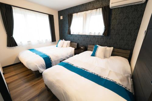 a hotel room with two beds and two windows at Guest House TEINE Nisimiyanosawa 41 最大11名滞在 無料駐車場2台完備 TEINE Ski Resort車で15分 in Sapporo
