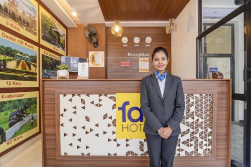 a woman in a suit standing in front of a sign at FabHotel NRM Residency in Mysore