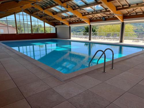 une grande piscine avec de l'eau bleue dans un immeuble dans l'établissement L'Erable T2 climatisé, à Trébas