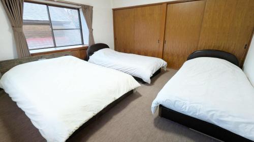 a bedroom with two beds with white sheets and a window at コテージ自給自足 伊根 in Nomuro