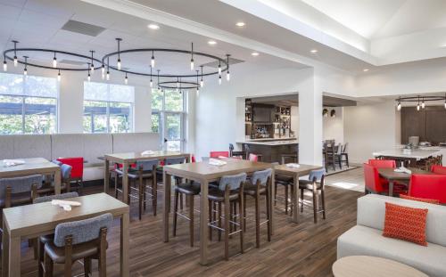 a restaurant with wooden tables and red chairs at Hilton Garden Inn Des Moines/Urbandale in Urbandale