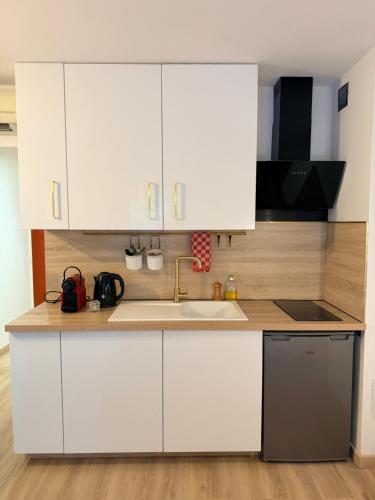 Una cocina con gabinetes blancos y un fregadero. en Le Clos d'AIX studio 1, en Aix-en-Provence