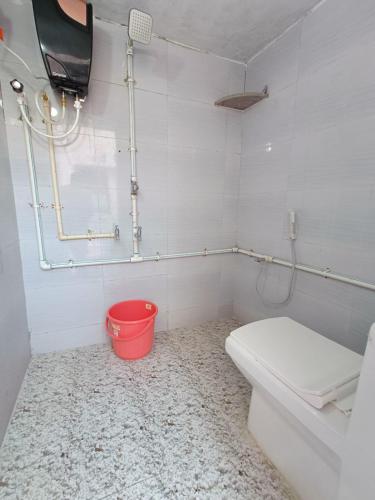 a bathroom with a toilet and a red bucket at Adb's Kuzhlam Traditional Homestay & Rooms in Tiruchirappalli