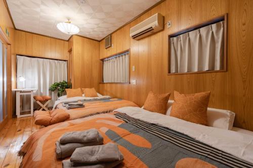 two beds in a room with wooden walls at NOKA stay MIZUE - オープン特別価格, 最大6名貸切, 浅草 東京 銀座 上野 30分, ディズニー 新宿 渋谷40分 in Tokyo