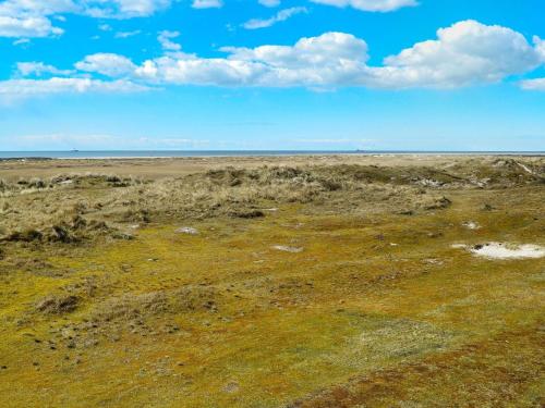 un campo abierto con hierba y un cielo azul con nubes en 4 person holiday home in Fanø, en Fanø