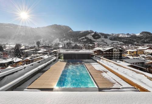 a swimming pool on top of a building in the snow at Schwarzer Adler Kitzbühel - Adults Only in Kitzbühel