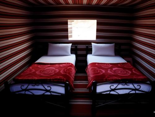 Golden Day Bedouin Camp في وادي رم: سريرين في غرفة صغيرة بها نافذة