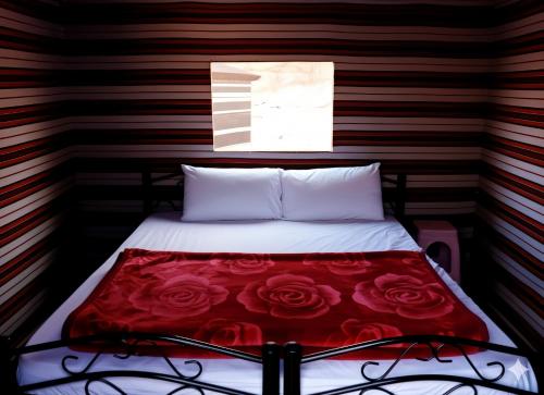 Golden Day Bedouin Camp في وادي رم: غرفة نوم بها سرير عليه ورود حمراء