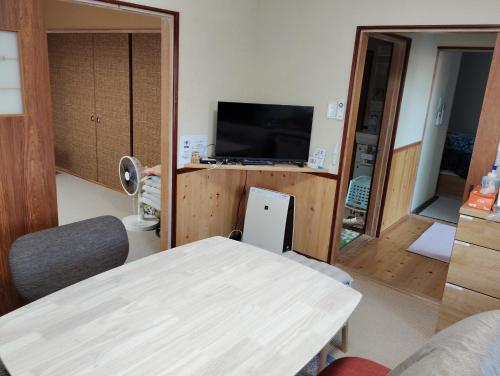 a room with a table and a tv in a room at Hermit 知床 in Shari